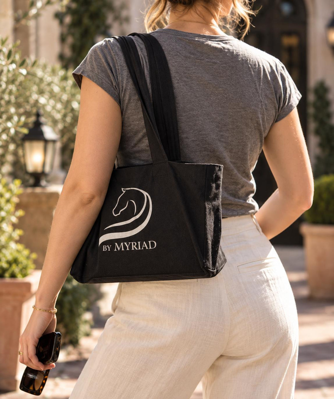 Black canvas tote bag with the by Myriad logo in reflective silver