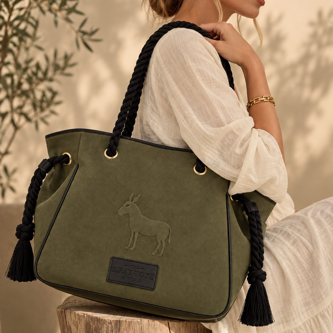 Woman in a cream top carrying the Bray tote in olive faux suede on her shoulder