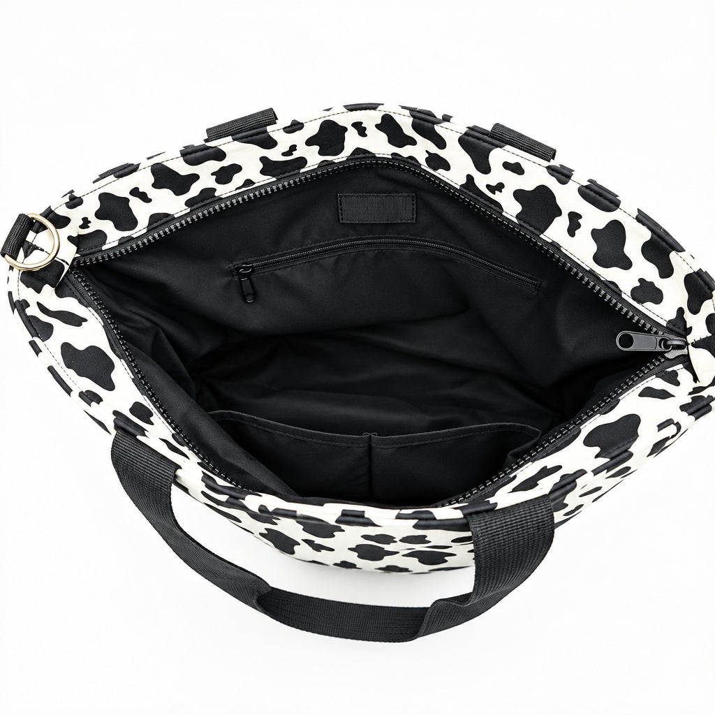 Inside the Dublin cow print tote: black lining with slip pockets and a zipper pocket