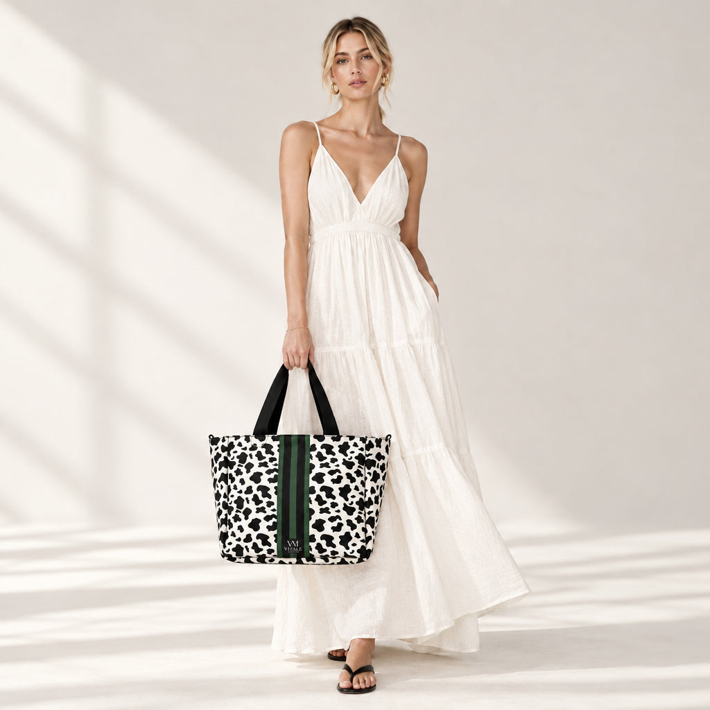 Woman in a white maxi dress carrying the Vitale by Myriad Dublin cow print tote with a green stripe