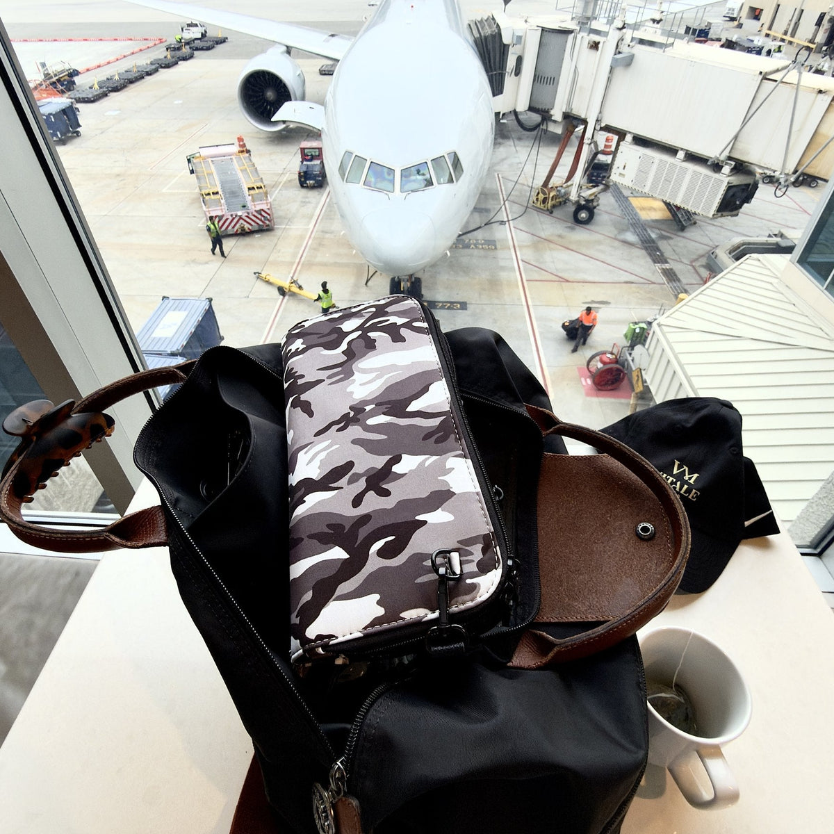 Eros black camo RFID neoprene crossbody on a travel bag at an airport gate