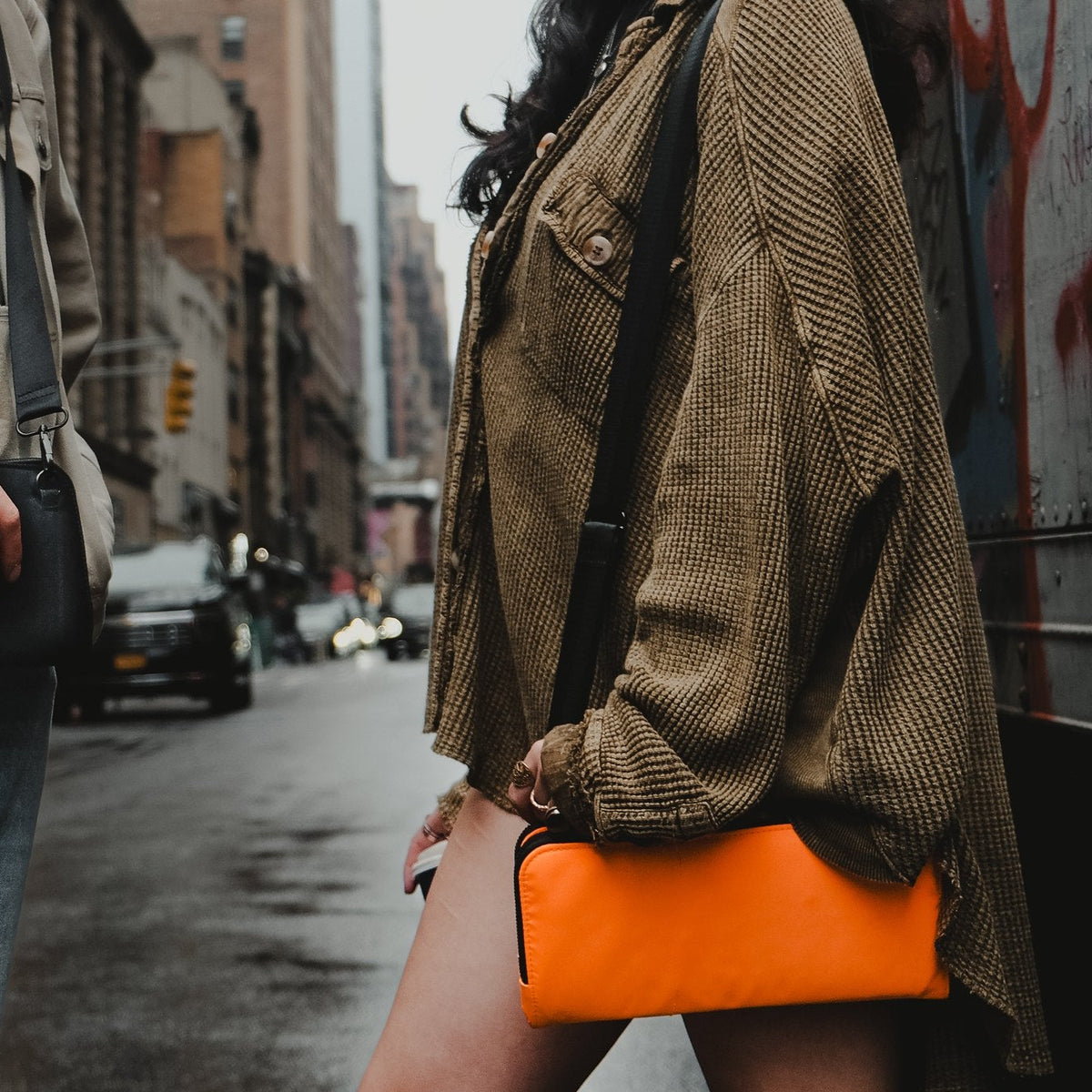 Two friends on a city street wearing the Eros black and Eros orange nylon crossbody bags