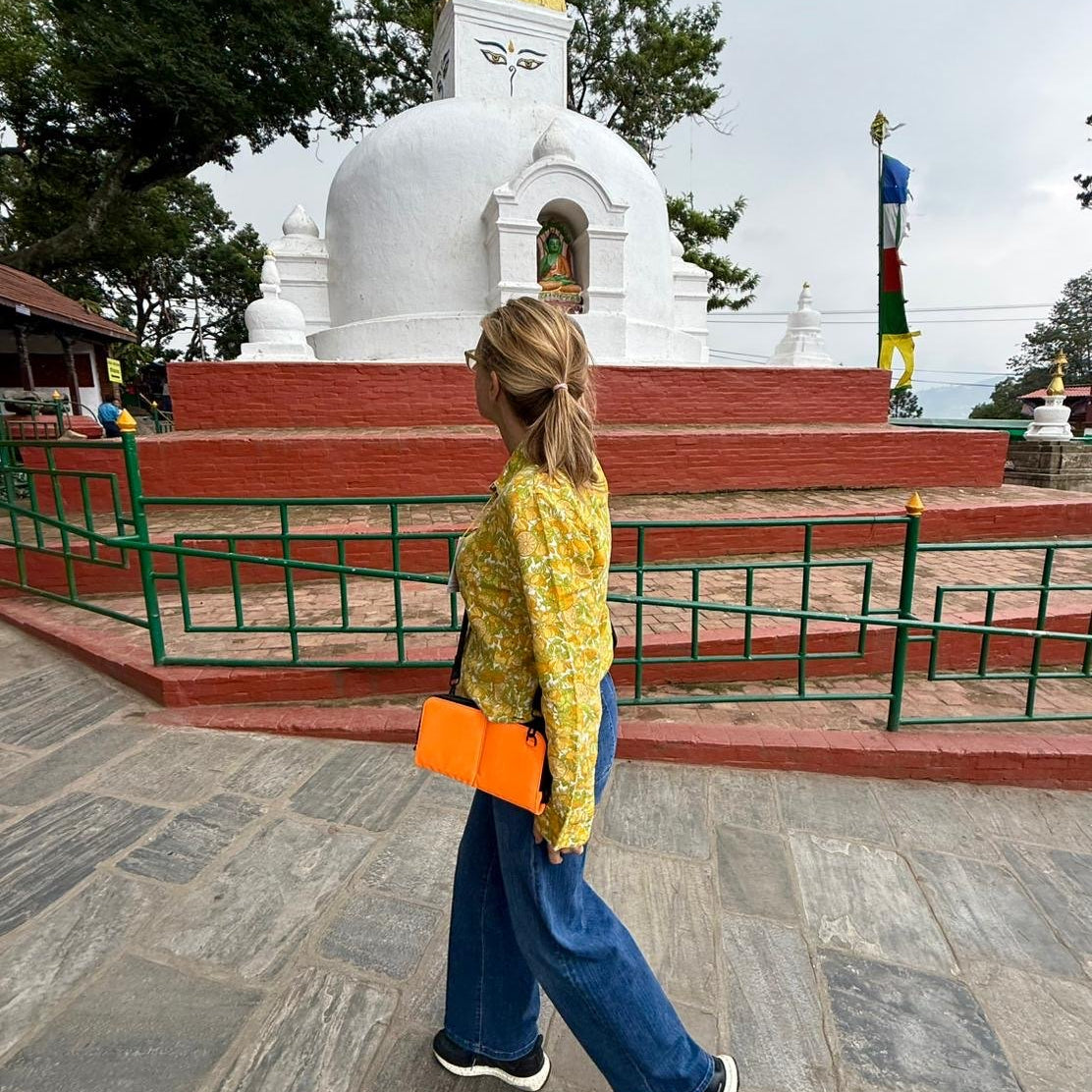 Woman in Nepal wearing the Eros orange nylon crossbody on its strap