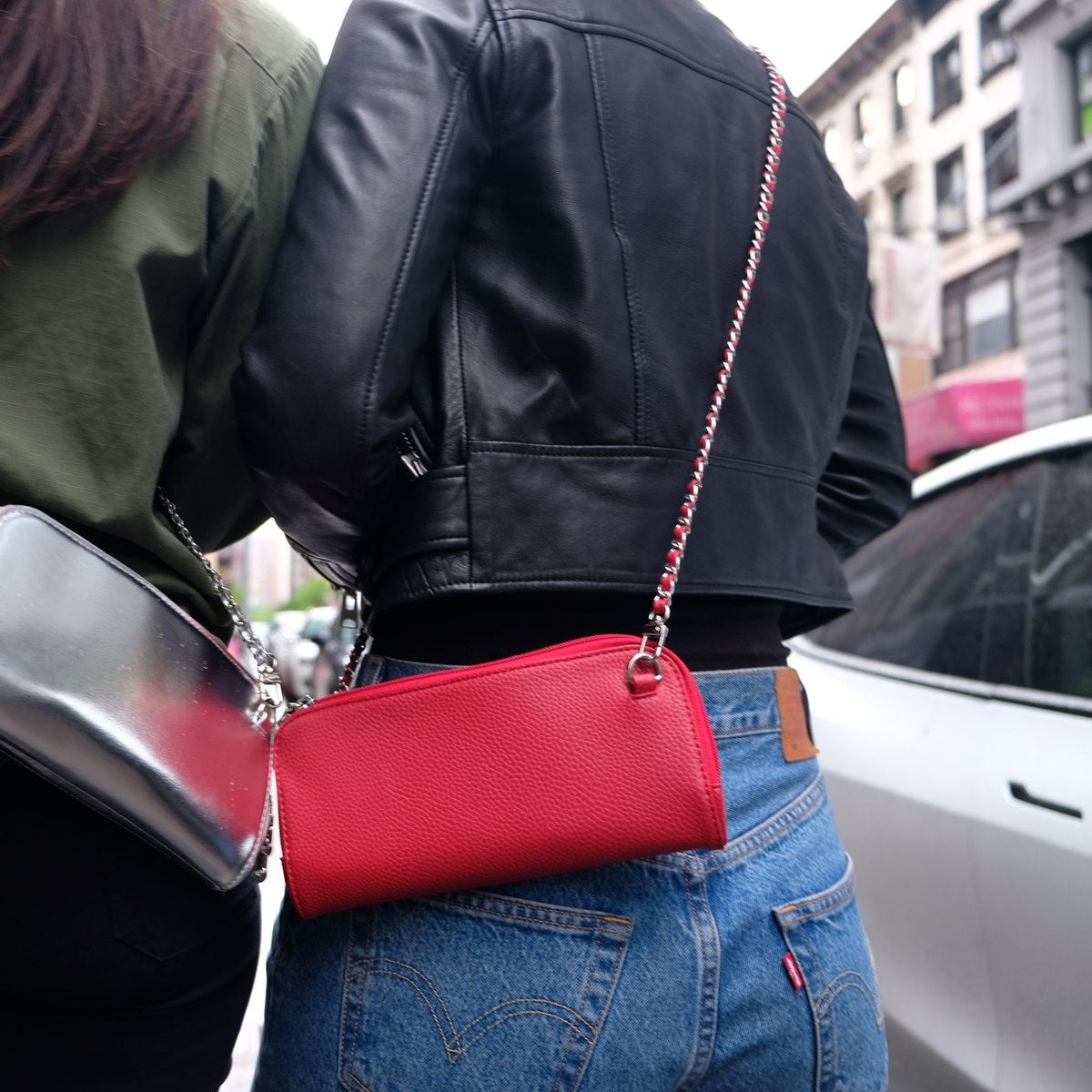 Back view of two friends wearing the Hestia scarlet red and Hestia silver metallic mini crossbody bags