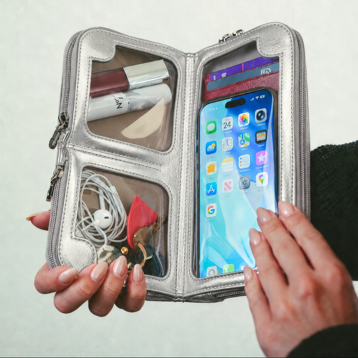 Hands using a phone through the touchscreen window of the open Hestia silver metallic mini crossbody