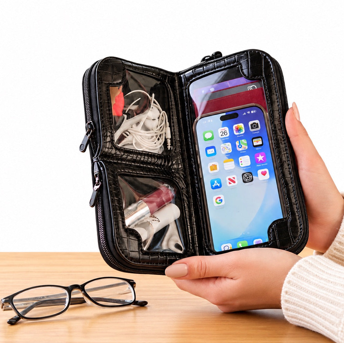 Hands holding the Osmand black shiny croc mini open on a table, phone in the touchscreen pocket, essentials above