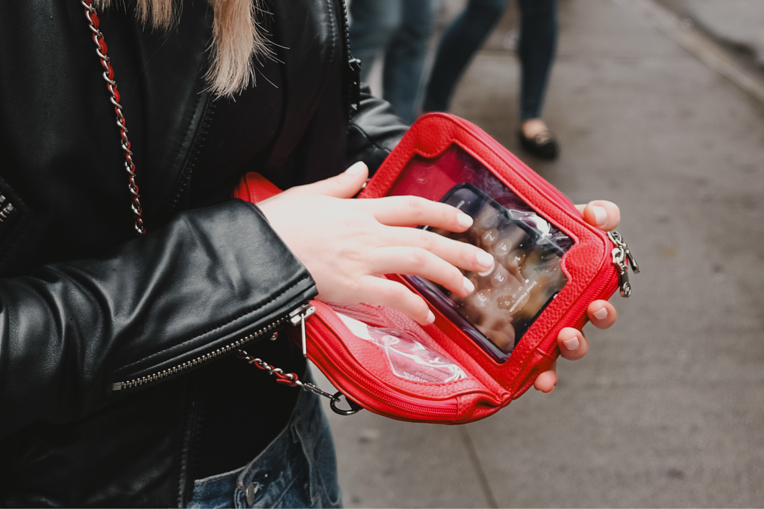 Vitale by Myriad red shoulder bag street style - using phone through clear compartment in vegan leather handbag