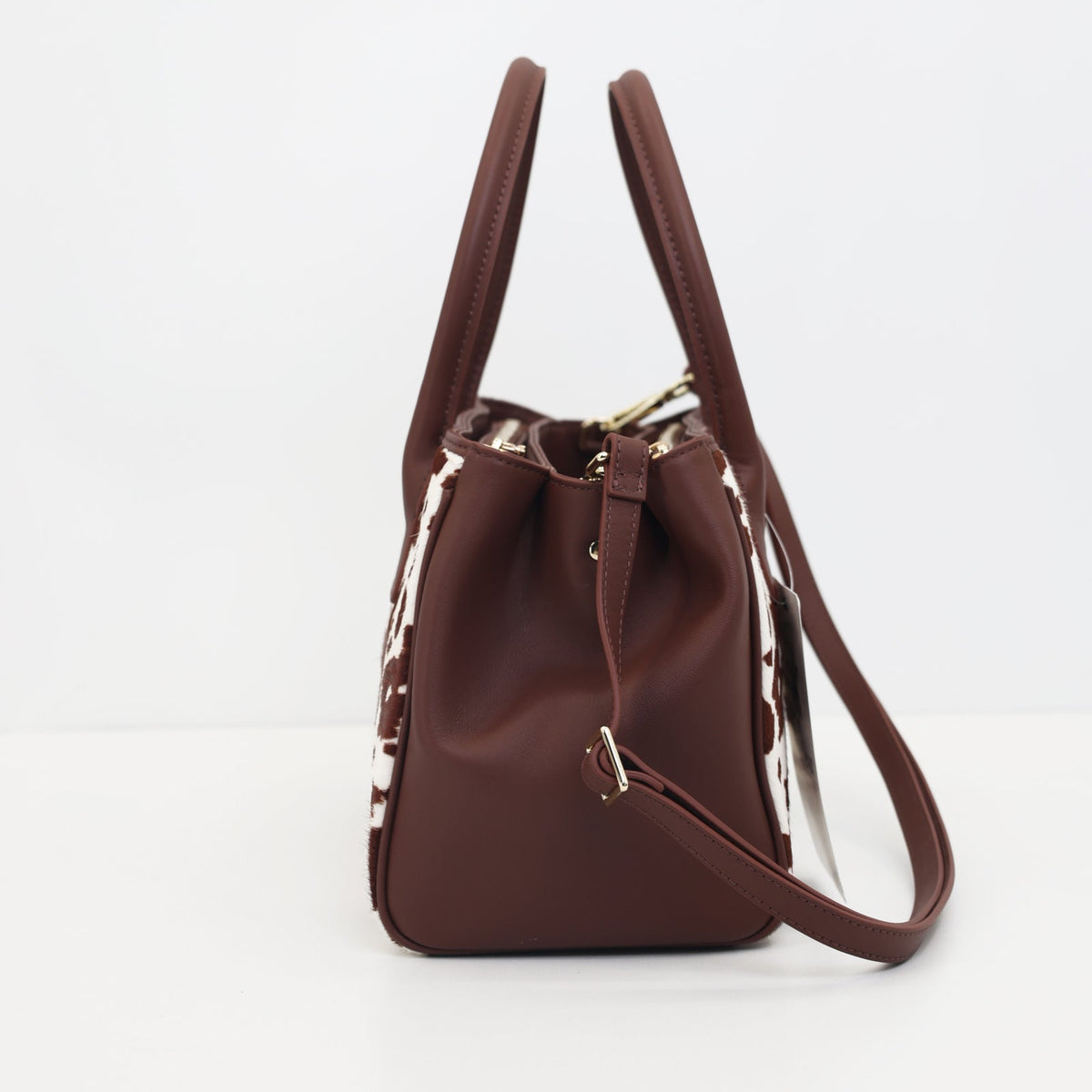Side view of the Roma brown cow hair-on-hide tote with its two top handles standing