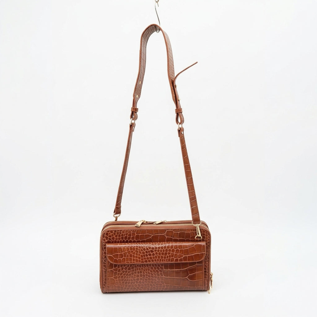 Vallina croc-embossed crossbody in cognac with its adjustable strap extended, on a white background