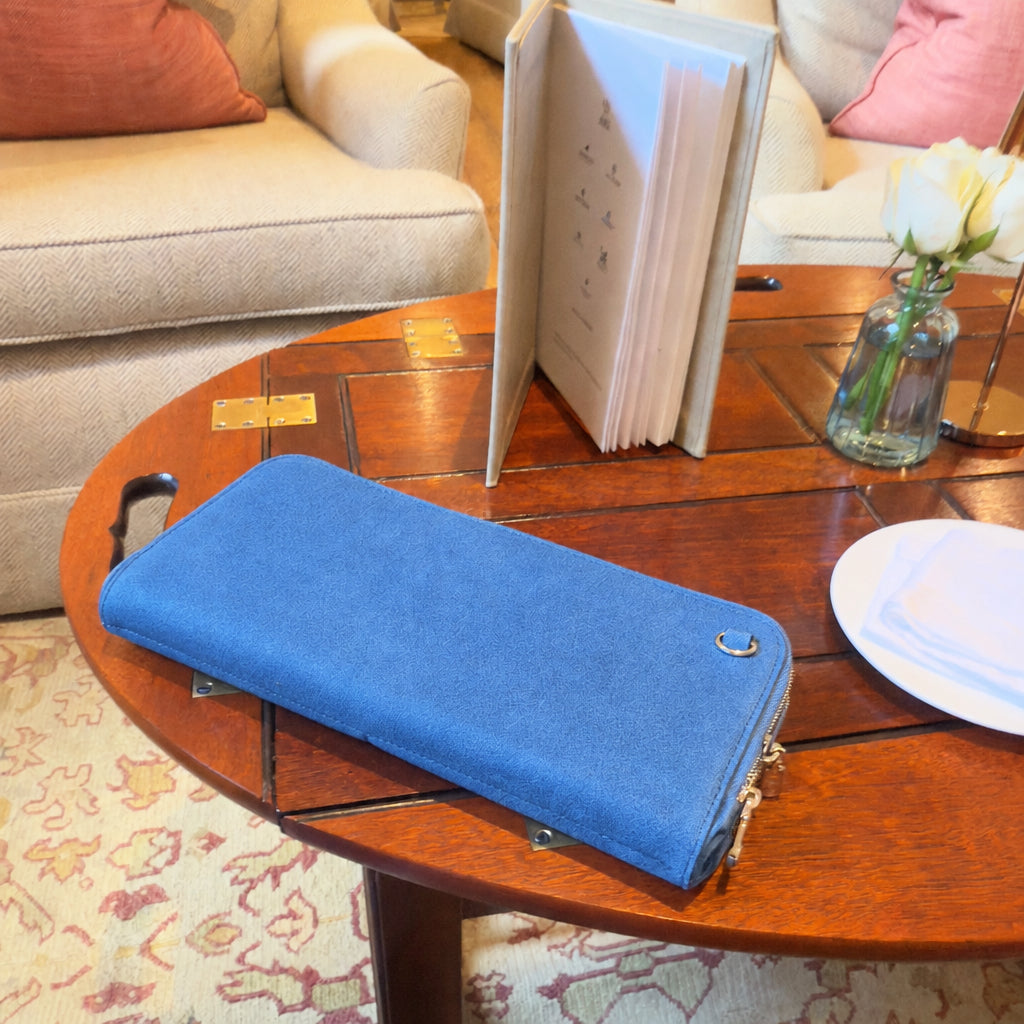 Zeloso Denim leather clutch closed on a round wooden table