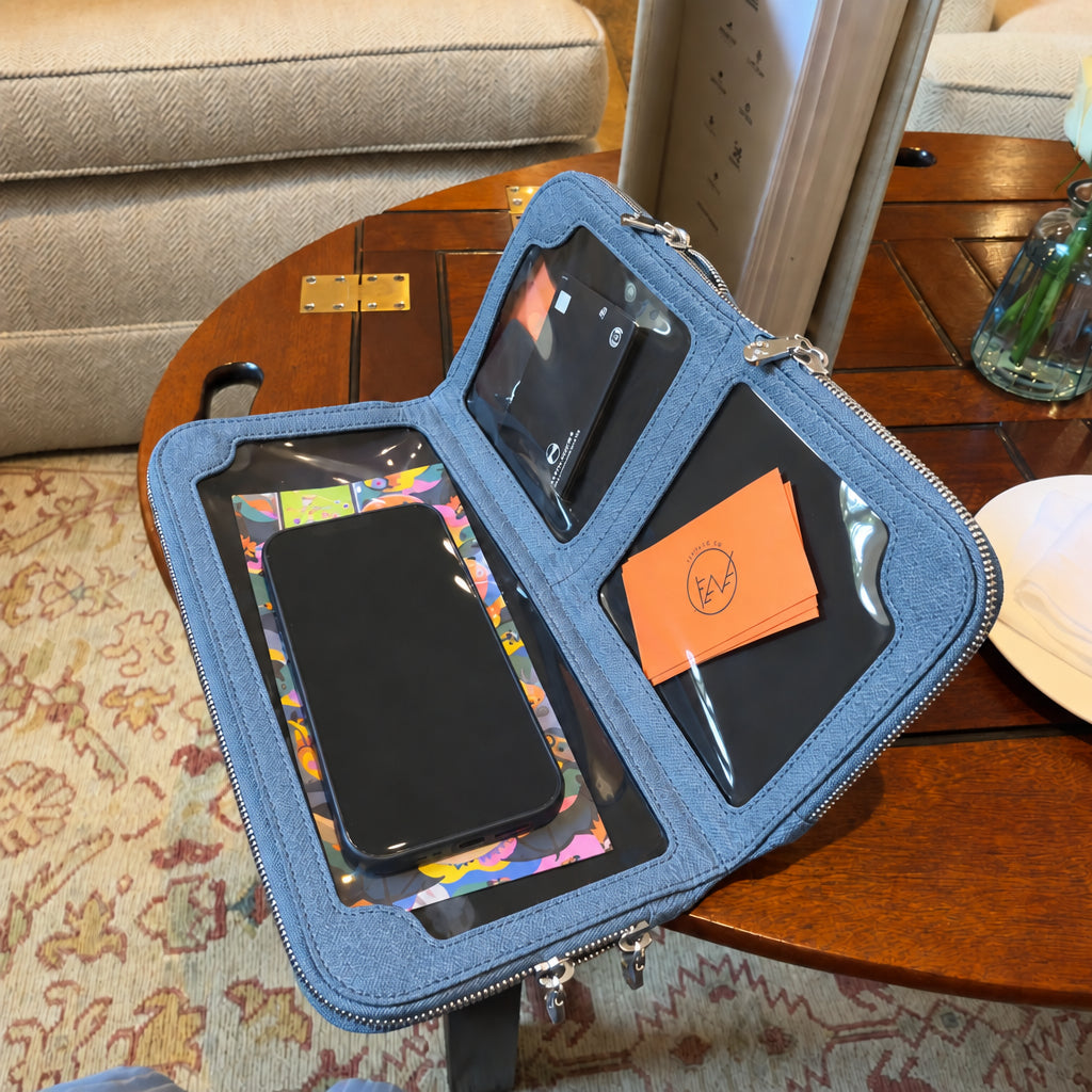 Zeloso Denim leather clutch open on a table, showing the touchscreen phone window and compartments